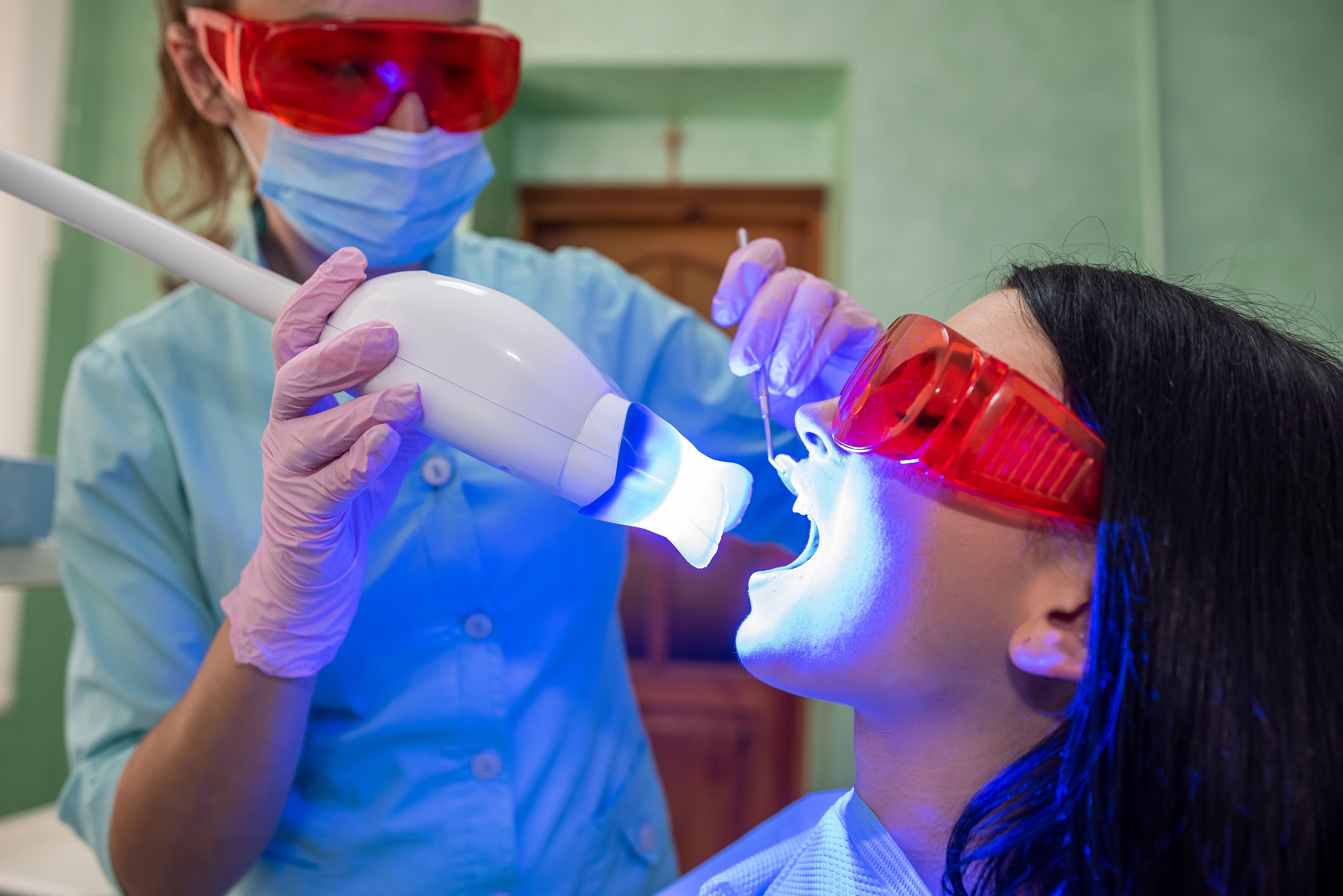 doctor-with-lamp-mirror-treating-patients-teeth-close-up.jpg